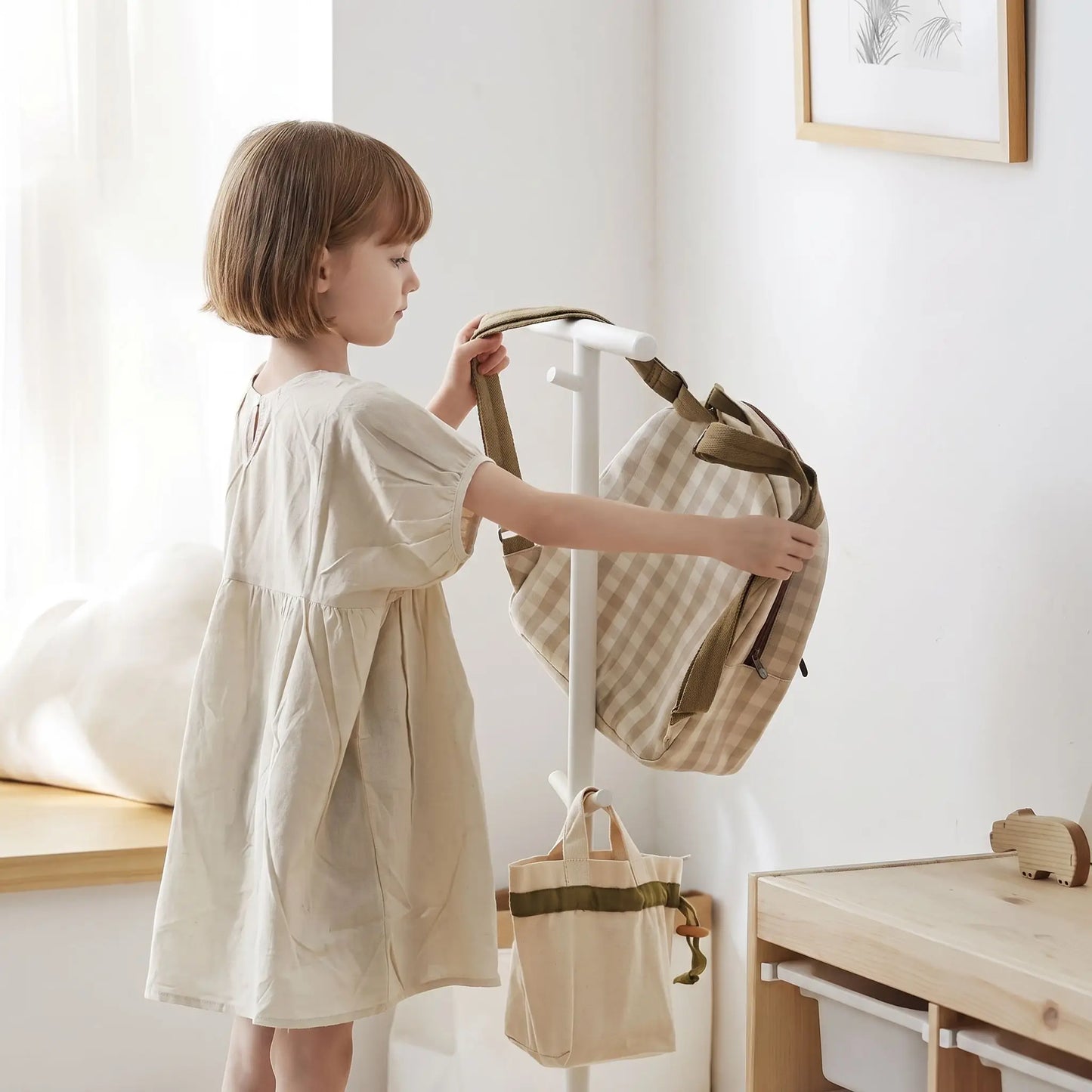 Porte‑manteau enfant LYKKE sur pied stable et évolutif en acier carbone premium avec fillette qui range son sac
