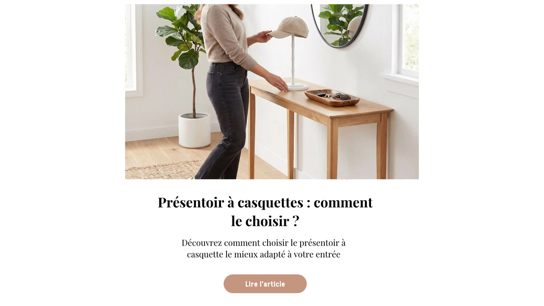 Présentoir à casquette posé sur une console en bois dans une entrée minimaliste, avec une casquette beige ajustée et un miroir rond en arrière-plan.