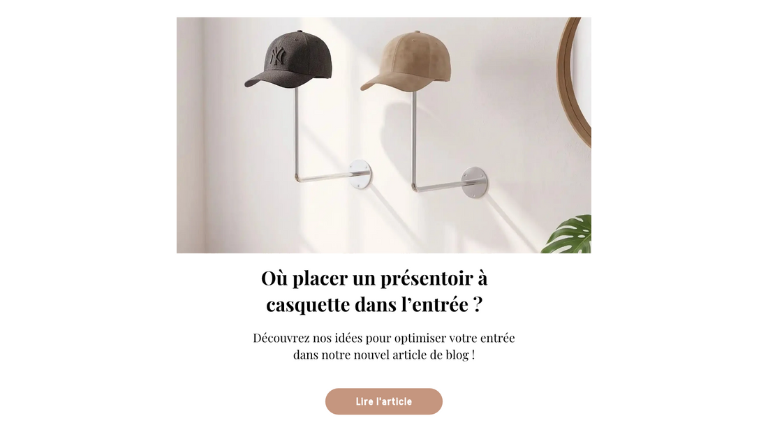 Présentoir à casquette mural avec deux casquettes exposées dans une entrée minimaliste, près d’un miroir rond et d’une plante.
