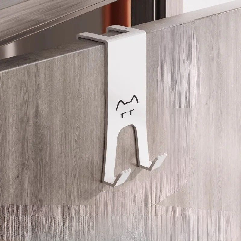 Crochet de porte sans perçage en forme de chat, design minimaliste avec deux crochets, fixé sur une porte.