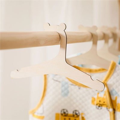 Infographie du cintre bébé en bois naturel montrant les encoches antidérapantes et la finition polie pour vêtements d'enfant.