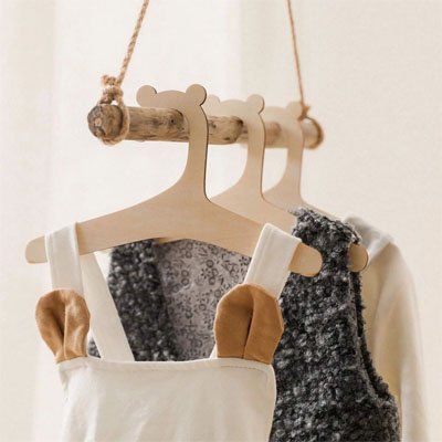 Cintre bébé en bois naturel avec un vêtement d'enfant suspendu pour l'organisation du vestiaire d'entrée