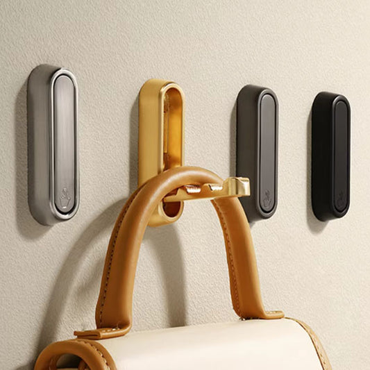 Plusieurs crochets muraux pliables InvisibleHook™ en Noir, Doré et Argent installés sur un mur, supportant les anses d'un sac à main.