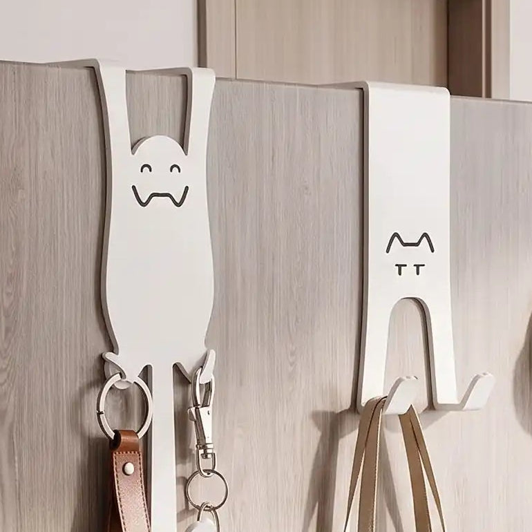 Crochets de porte sans perçage en forme de chat, utilisés dans une entrée moderne pour accrocher accessoires du quotidien.