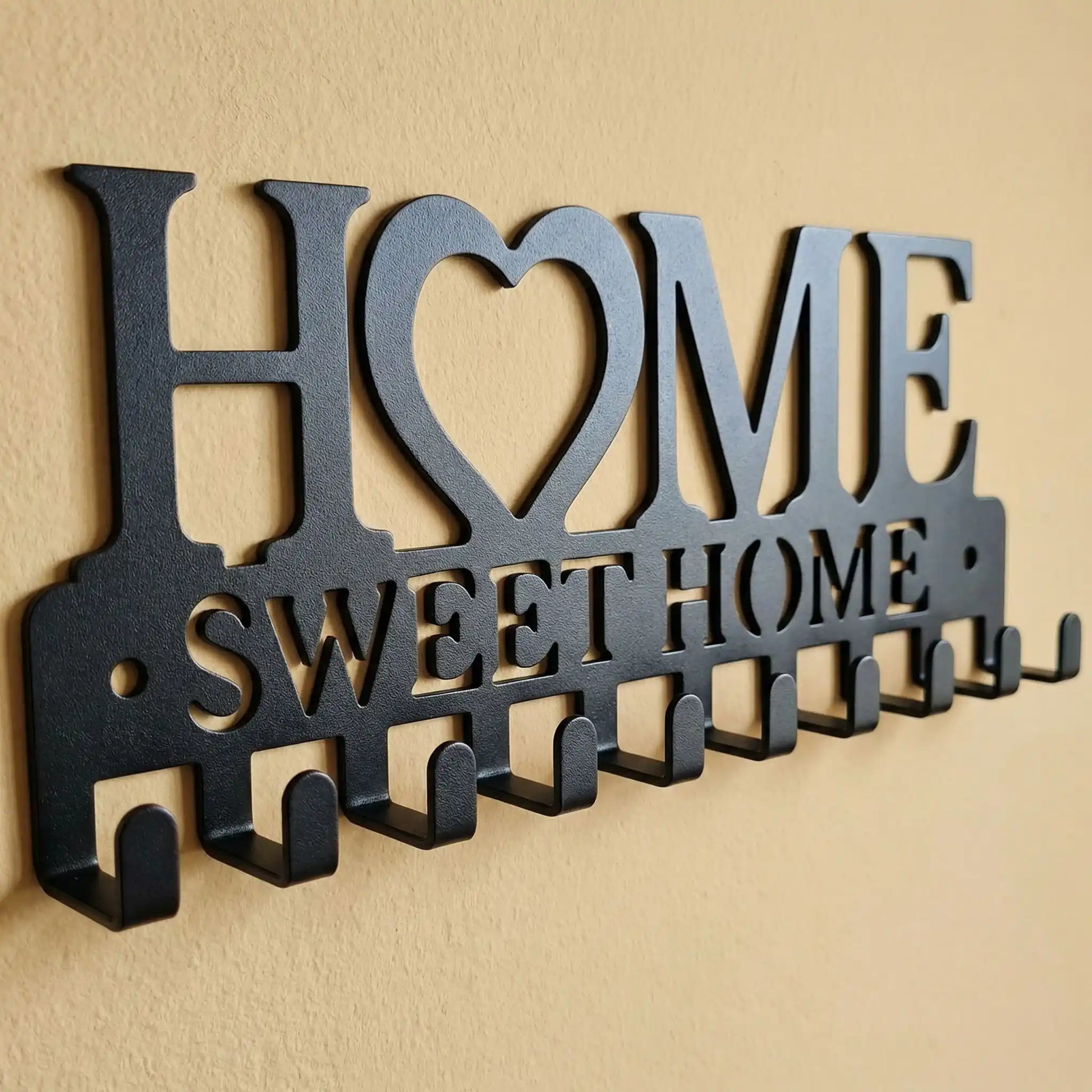 Gros plan du porte-clés mural Sweet Home en métal noir montrant les 10 crochets robustes et la découpe laser de précision.