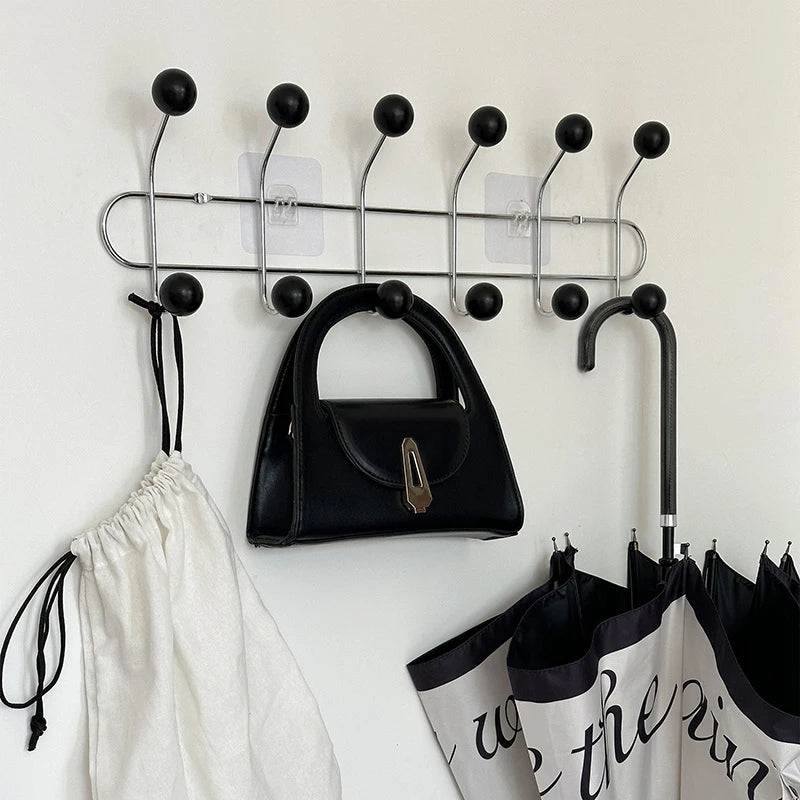 Patère porte-manteau murale design « Vintage Élégance » avec 6 crochets noirs, fixée sur un mur clair.