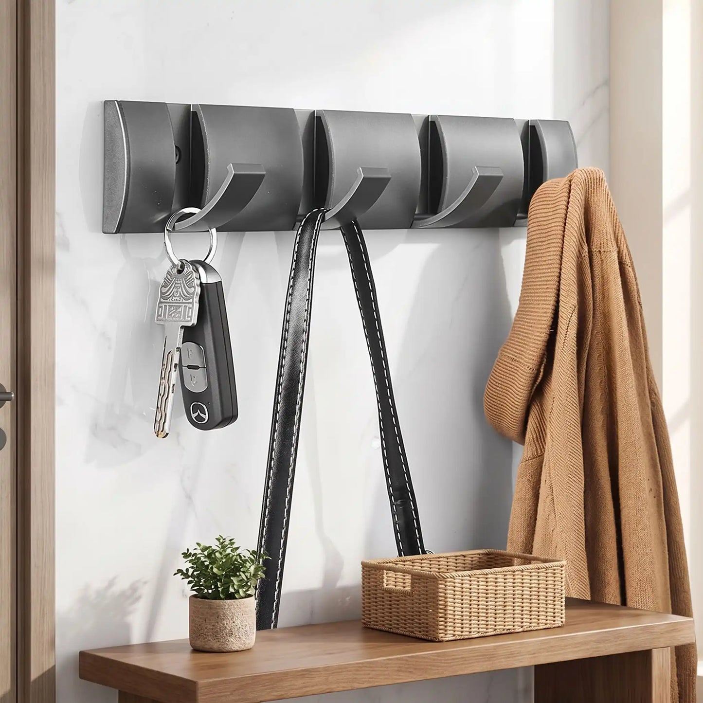 Patère murale compacte en aluminium gris avec quatre crochets escamotables alignés, vue de face sur fond blanc.