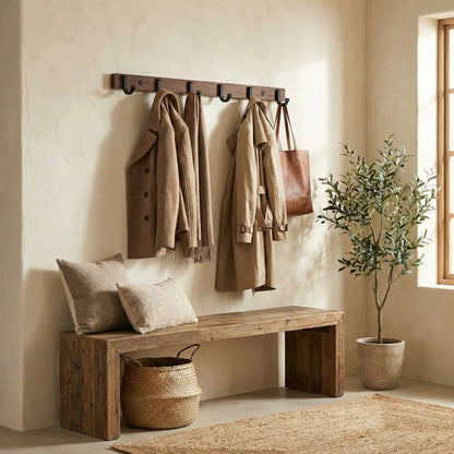 Patère murale moderne en bois et métal noir avec manteaux, écharpes et sac dans une entrée lumineuse avec un banc et une plante