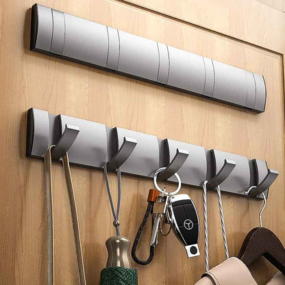 Patère porte-manteau mural en aluminium gris avec 5 crochets repliables installée sur un mur en bois.
