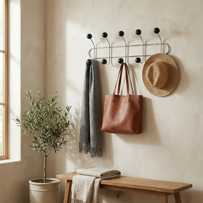 Patère porte-manteau murale style industriel avec crochets noirs et structure en bois dans une entrée décorée.
