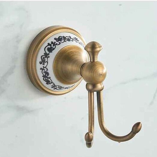 Patère victorienne double en laiton et céramique fixée sur un mur clair dans une salle de bain élégante