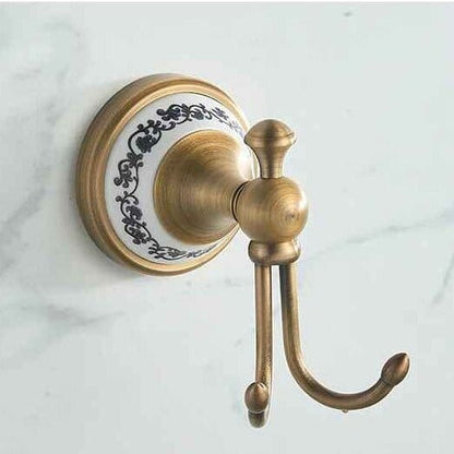 Patère victorienne double en laiton et céramique fixée sur un mur clair dans une salle de bain élégante