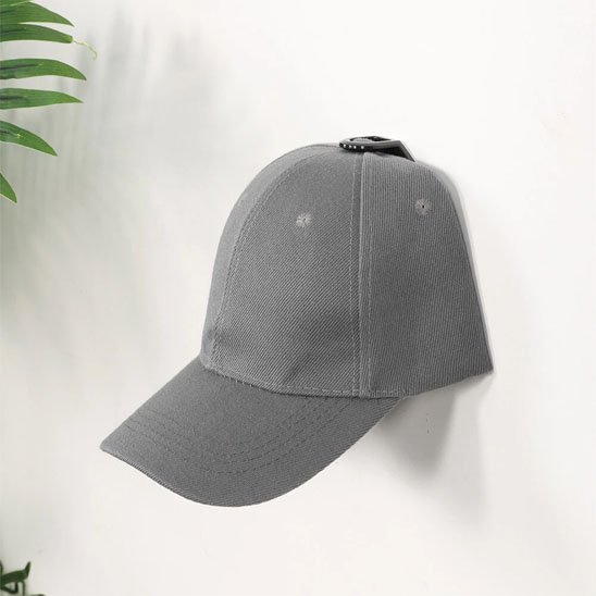 Exemple d'installation du porte casquette OrganizPro avec une casquette de sport grise, montrant l'effet de suspension invisible sur un mur blanc.