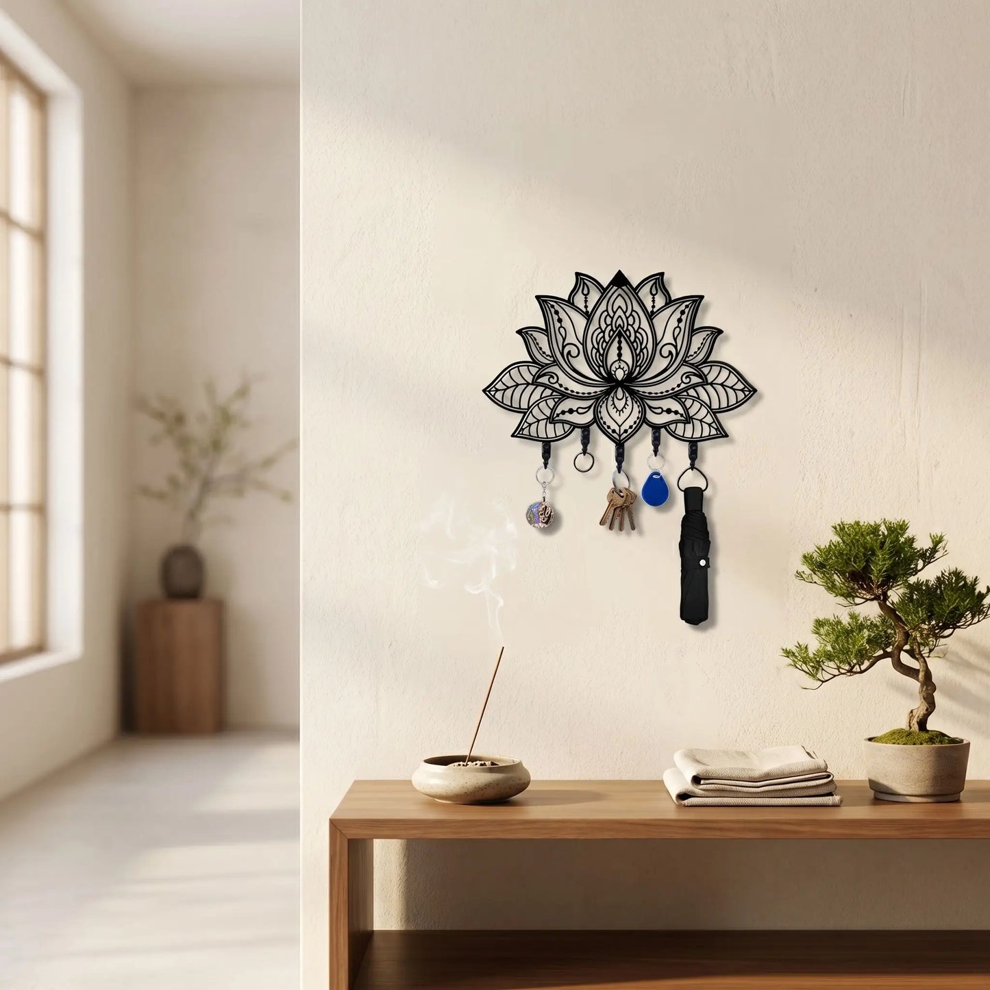 Porte-clé mural Lotus en métal noir avec 5 crochets, exposé dans un décor zen avec un bonsaï, de l'encens et un meuble en bois moderne