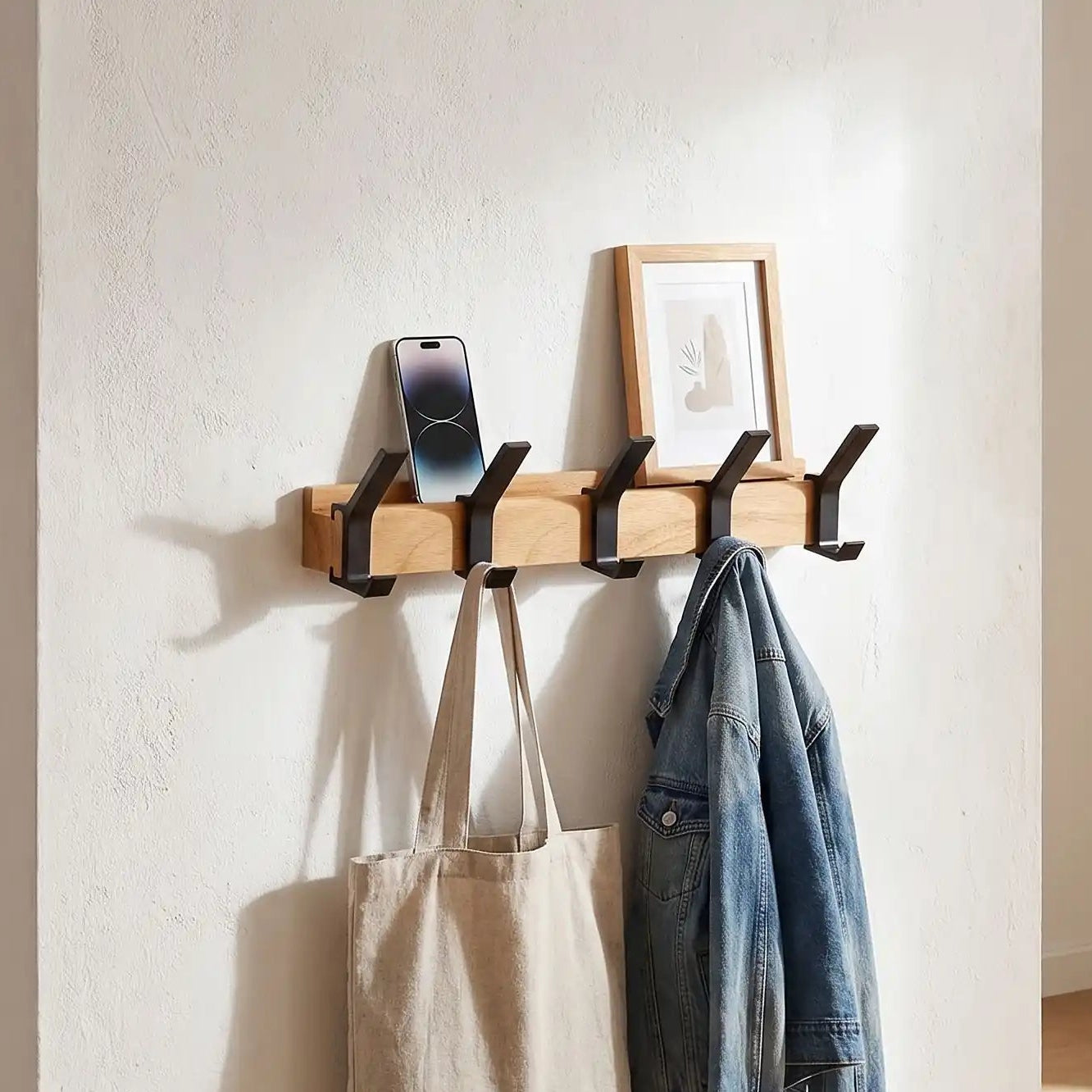 Porte-manteau mural en bois massif MobileHook dans une entrée lumineuse avec décoration minimaliste et crochets noirs.