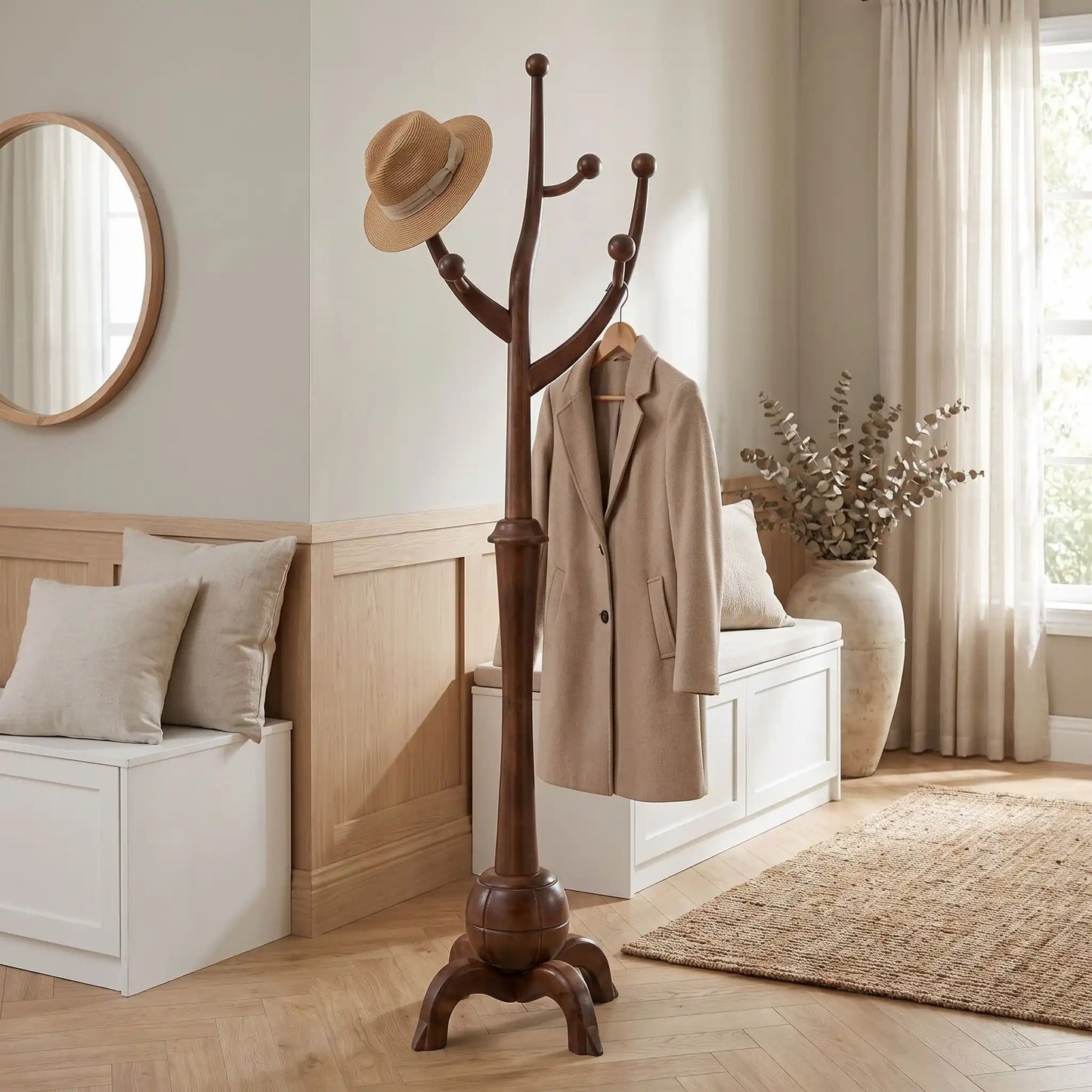 Porte‑manteau en bois massif sculpté avec manteaux et chapeau dans une entrée élégante.