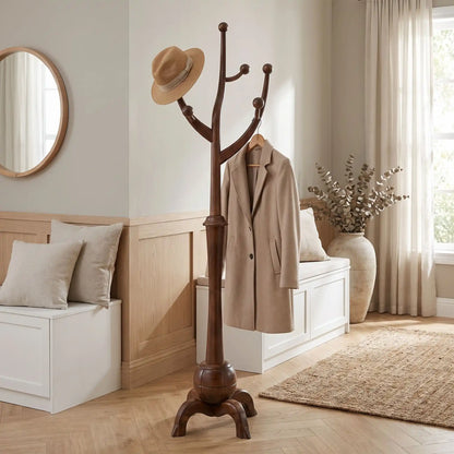 Porte‑manteau en bois massif sculpté avec manteaux et chapeau dans une entrée élégante.