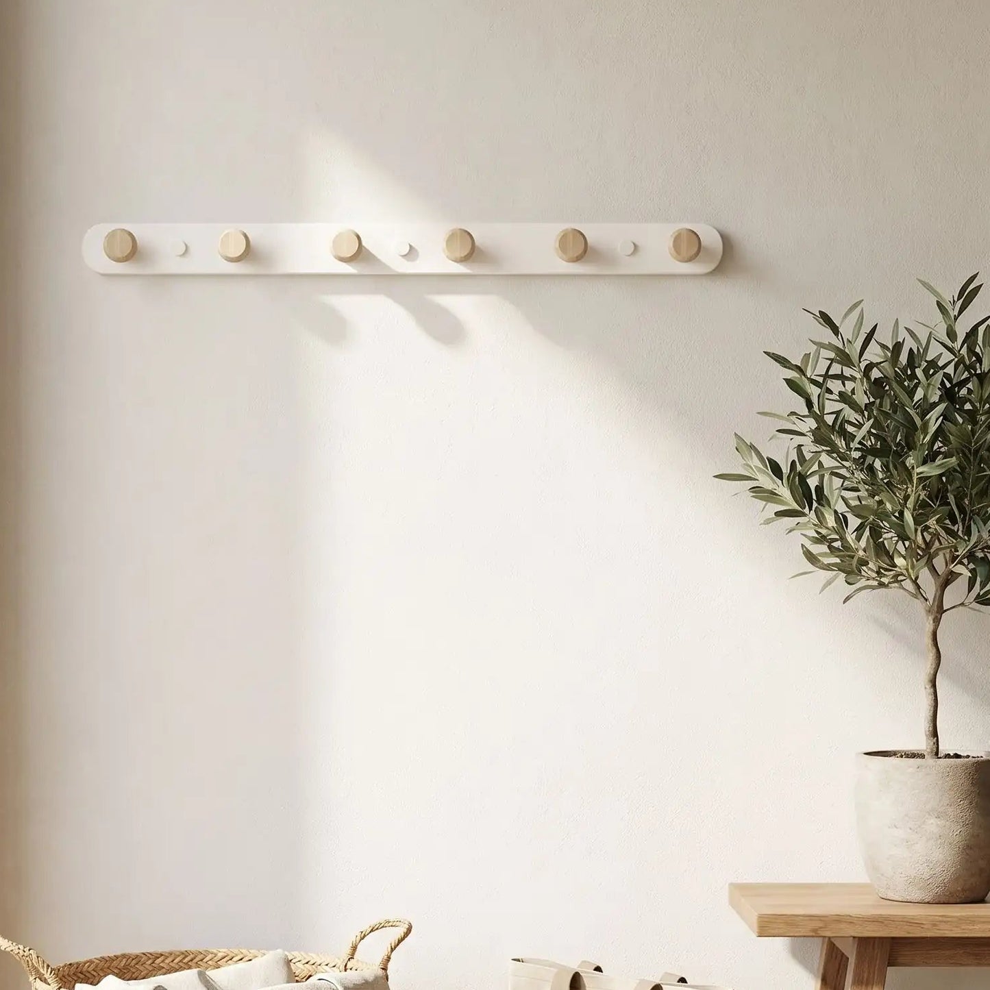Porte-manteau mural 6 crochets en bois et blanc installé dans une entrée lumineuse à côté d'une plante verte.