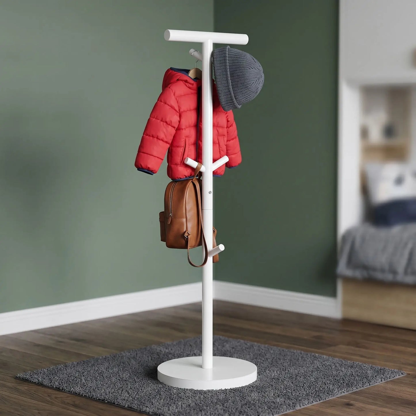 Porte-manteau enfant blanc sur pied en acier carbone avec une veste rouge et un sac à dos, montrant la stabilité du meuble.
