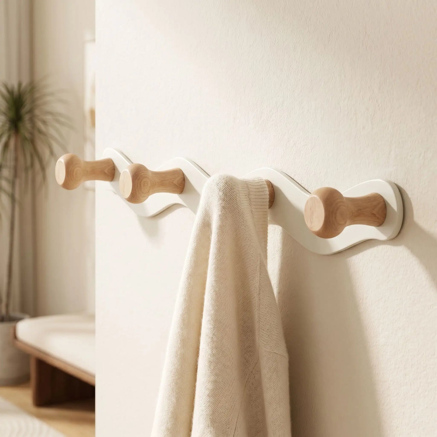 Zoom sur un crochet en bois naturel du porte-manteau CréativeWaves supportant un vêtement délicat en laine.