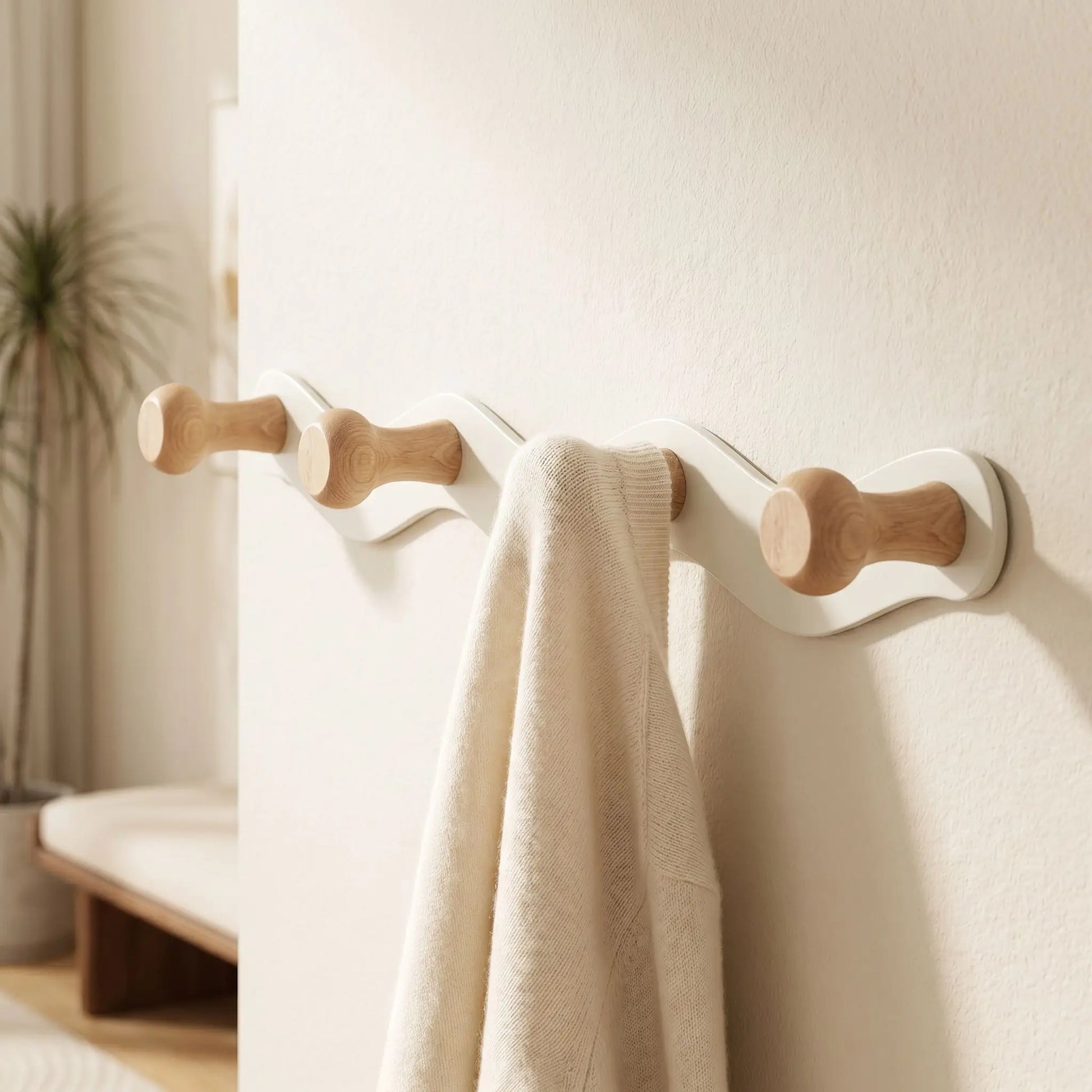Zoom sur un crochet en bois naturel du porte-manteau CréativeWaves supportant un vêtement délicat en laine.