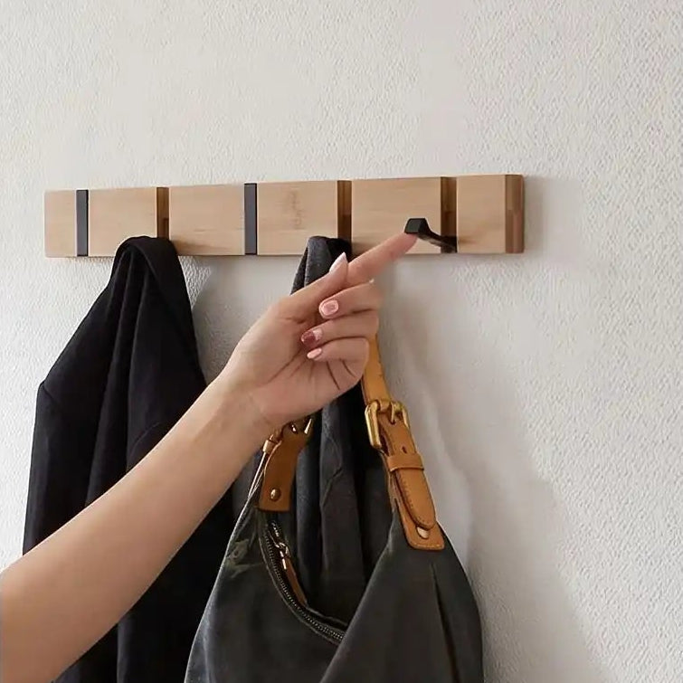 Main dépliant un crochet de porte-manteau mural bois bambou supportant un sac et une veste