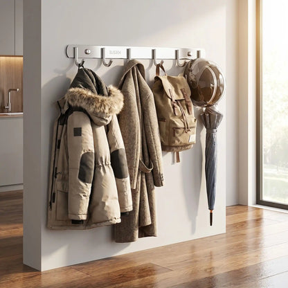 Porte-manteau mural Le Pêcheur en inox supportant plusieurs vêtements lourds : parka d'hiver, manteau long, sac à dos et parapluie, démontrant sa haute capacité de charge.