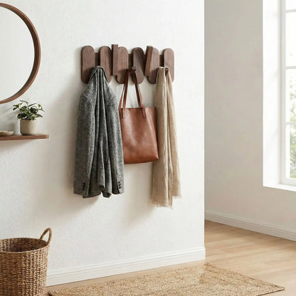 Porte-manteau mural design en noyer massif avec sac à main, veste grise et écharpe beige suspendus.