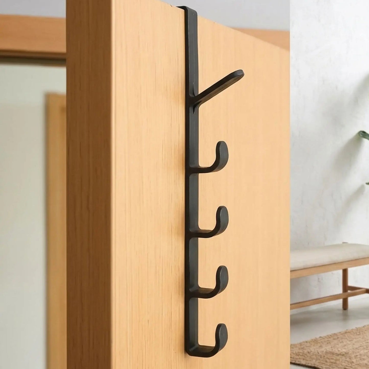 Gros plan du porte-manteau de porte Modèle Futé en noir carbone, montrant les 5 crochets de rangement installés sur une porte de chambre