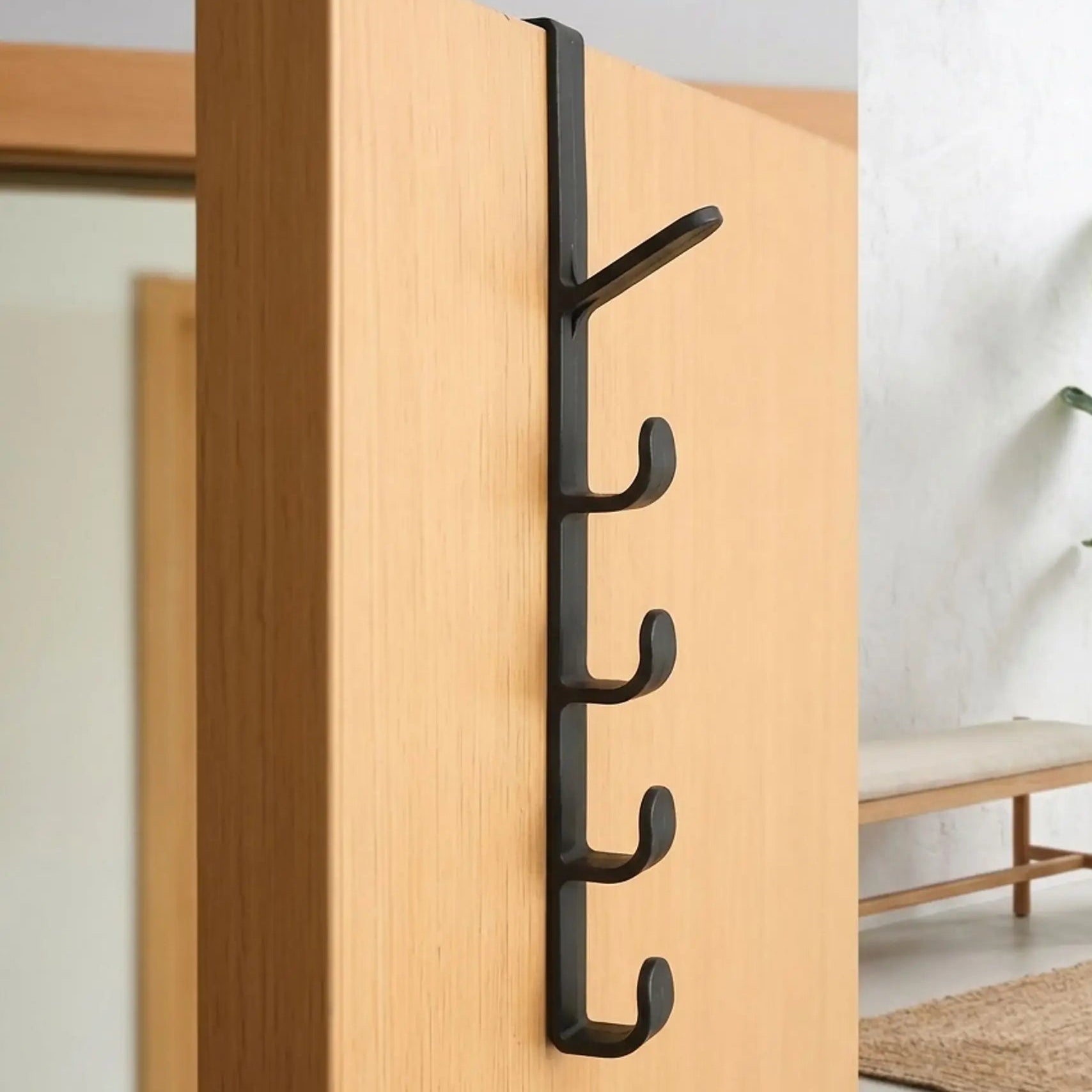 Gros plan du porte-manteau de porte Modèle Futé en noir carbone, montrant les 5 crochets de rangement installés sur une porte de chambre