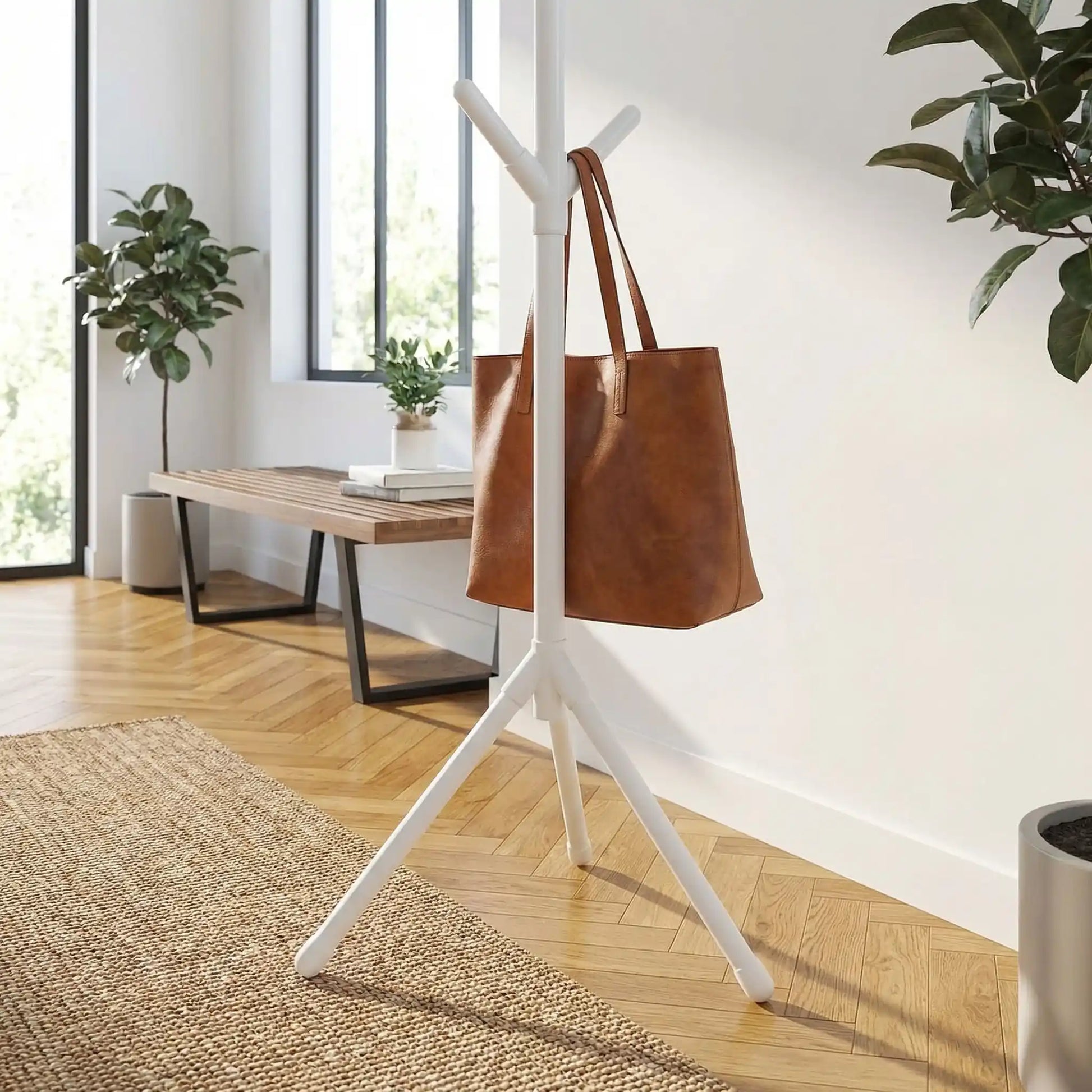 Porte-manteau sur pied blanc laqué au design branche avec sac en cuir marron suspendu, style scandinave et moderne.