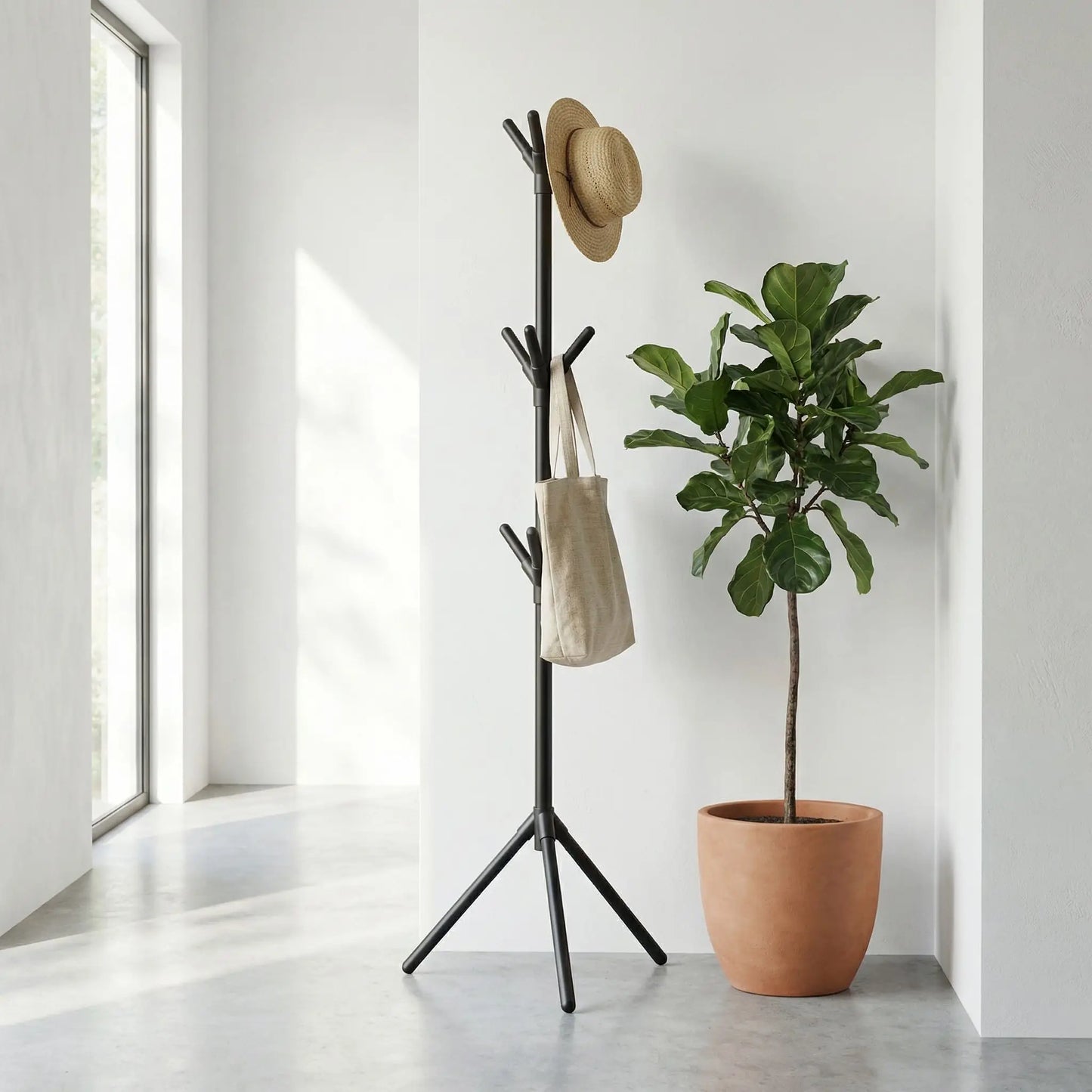 Porte-manteau sur pied noir mat au design organique avec chapeau et sac, installé à côté d'une plante verte dans une entrée moderne.