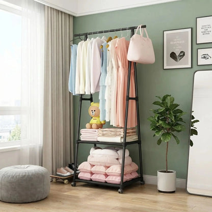 Porte-manteau sur pied noir avec vêtements et tablette de rangement dans une chambre lumineuse
