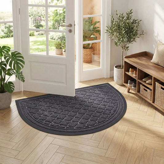 Décoration d'entrée avec un tapis demi-lune gris devant une porte blanche ouverte et un meuble de rangement à chaussures en bois.