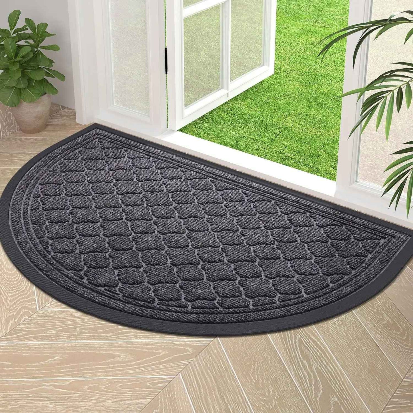 Tapis d'entrée demi-lune gris anthracite avec motif à vagues et bordure noire antidérapante devant une baie vitrée.