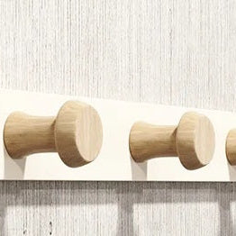 Gros plan sur les finitions d'un porte-manteau en bois de hêtre massif et ses crochets design, mettant en avant la qualité de fabrication.