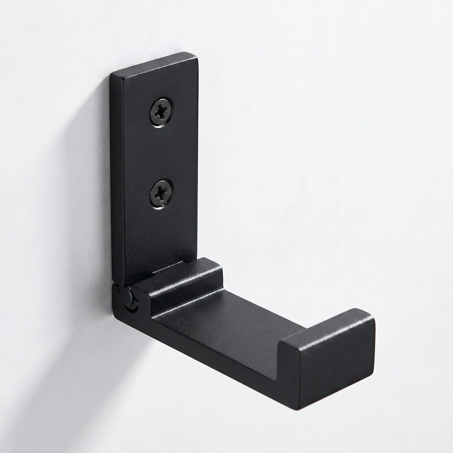 Gros plan sur le mécanisme d'une patère murale pliable noire Rangement Signature en alliage d'aluminium de qualité aéronautique.