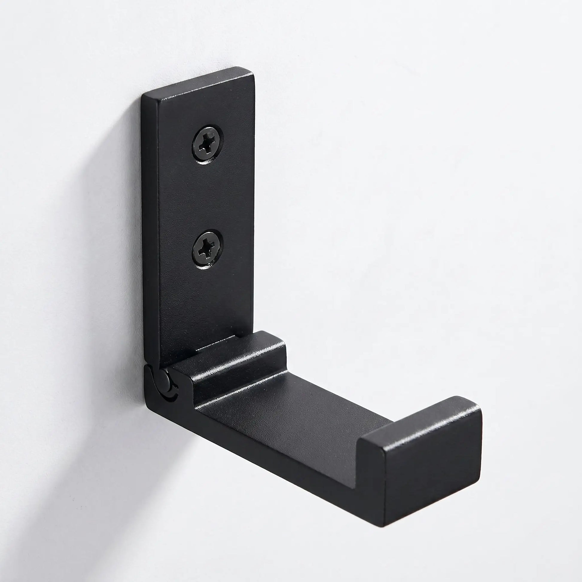Gros plan sur le mécanisme d'une patère murale pliable noire Rangement Signature en alliage d'aluminium de qualité aéronautique.